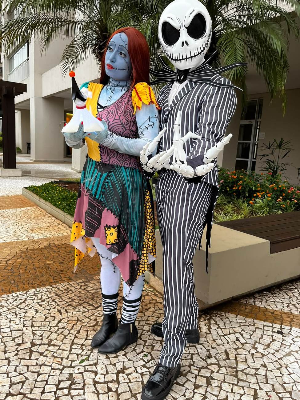Dupla do Halloween em trajes listrados posando ao ar livre entre palmeiras