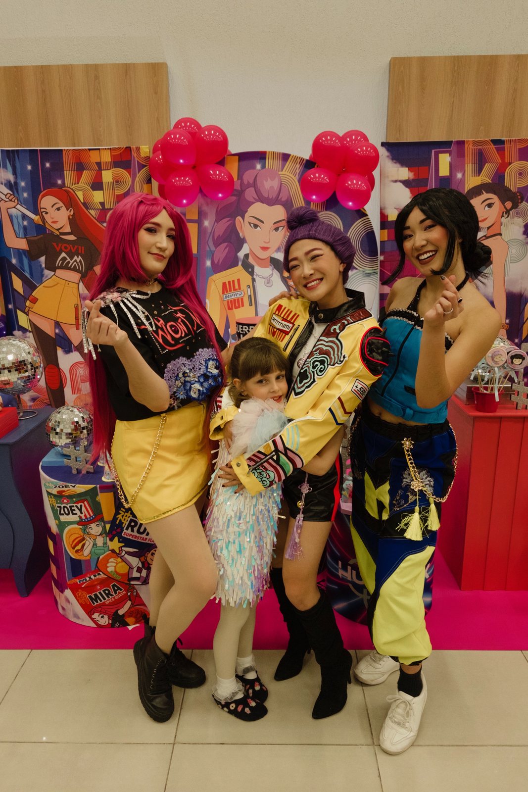 Personagem do Goku entre dois mascotes coloridos na festa