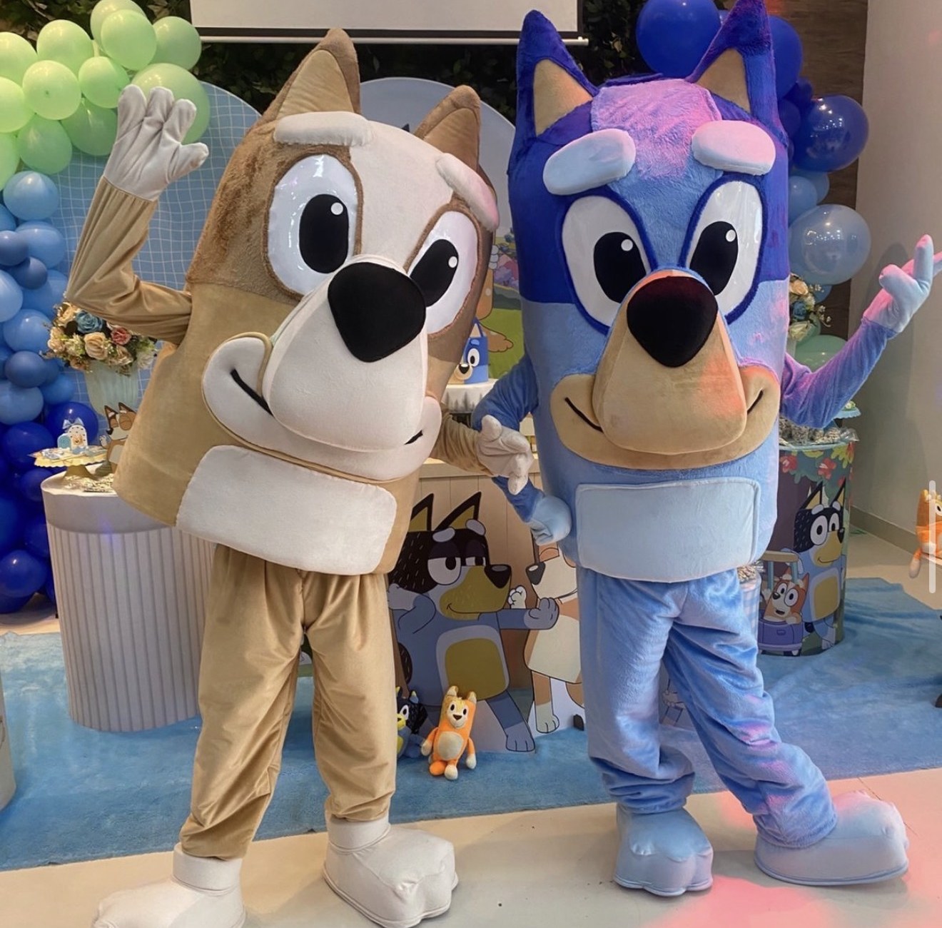 Mascotes de cachorrinhos azul e caramelo acenando na festa